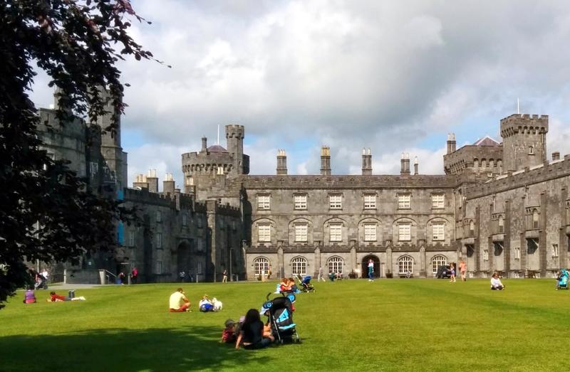 Pessoas a relaxar num relvado em frente a um castelo durante um curso de ingles na irlanda.