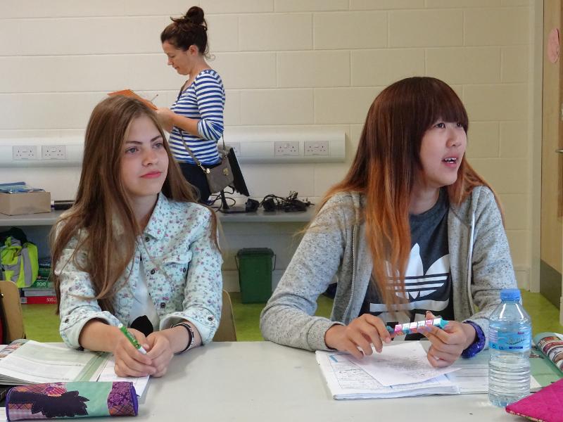 Jovens atentas numa aula durante um curso de ingles na irlanda, com materiais de estudo.