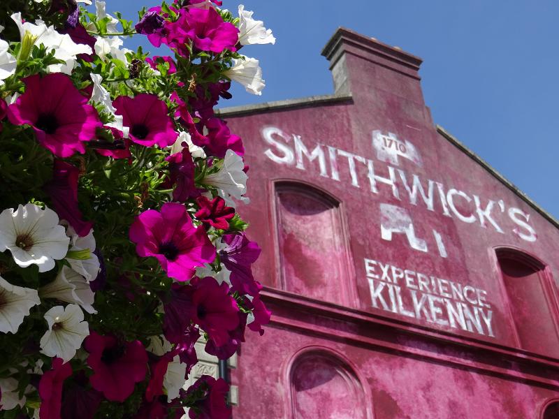 Fachada histórica da Smithwick's Experience em Kilkenny com flores vibrantes, durante um curso de ingles irlanda.