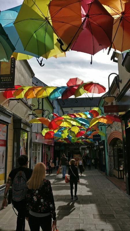 Rua decorada com guarda-chuvas coloridos suspensos num passeio de um curso de ingles irlanda.