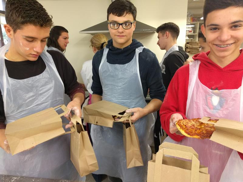 Jovens a participar numa atividade de culinária, segurando pizzas, num curso de ingles irlanda.