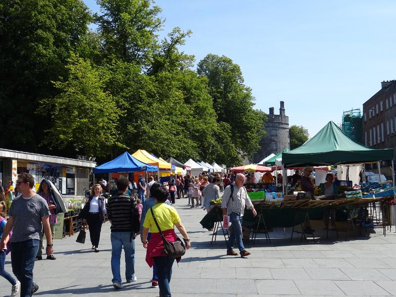 Mercado ao ar livre com várias tendas e visitantes durante um passeio de um curso de ingles irlanda.