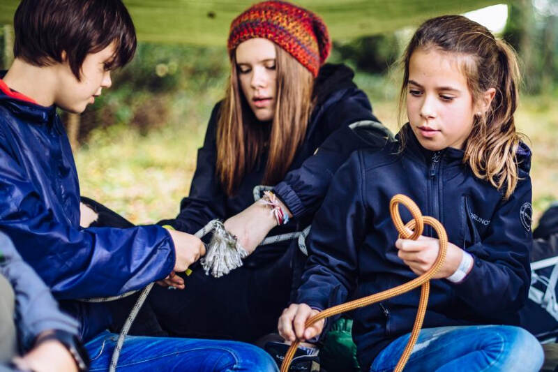 Jovens do campo de férias Madeira a aprender a dar nós nas cordas em grupo