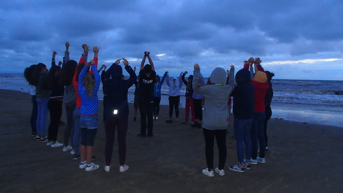 Grupo de jovens em círculo na areia da praia durante atividade de final de tarde no campo de férias Albergaria a Velha