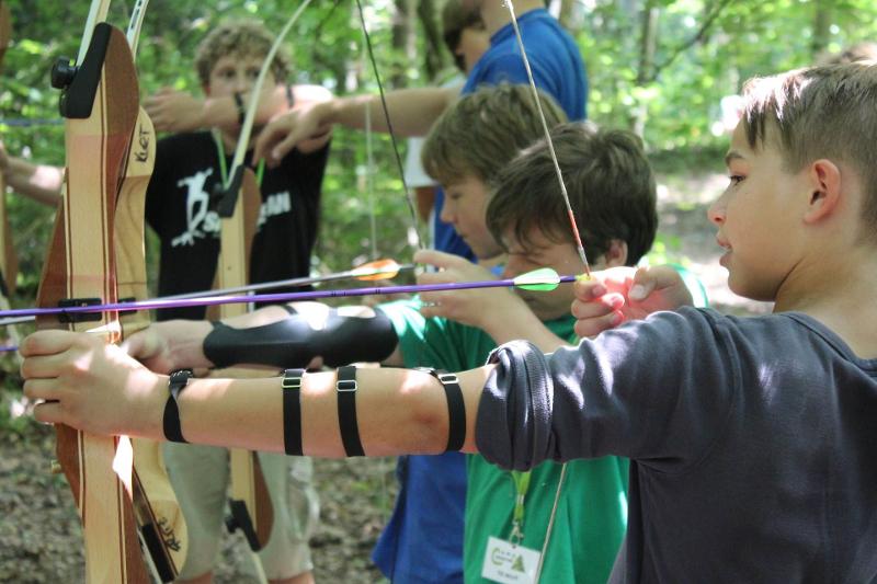 Crianças com o arco e flecha durante a atividade de grupo na colónia de férias em Inglês
