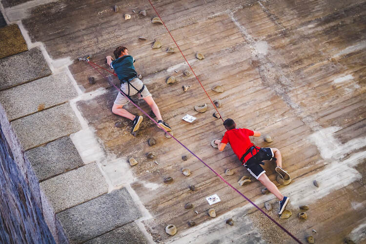 Dois jovens a subir a parede artificial durante atividade de escalada do campo de férias Cadaval