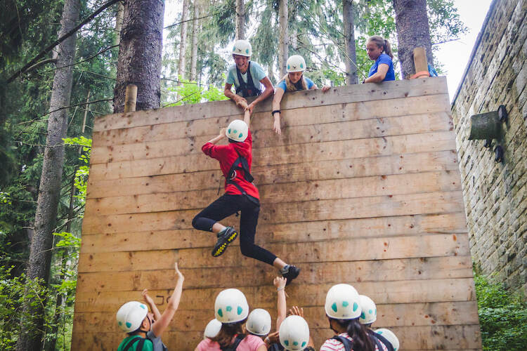 Jovem a passar uma barreira de madeira no campo de férias Vila Real 2025 durante atividade de equipa