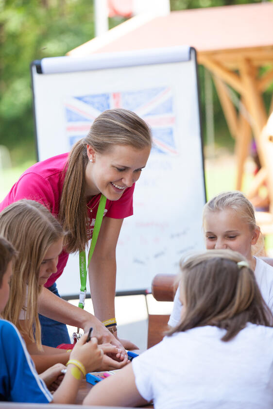 Professora a ajudar os jovens na atividade de inglês durante o campo de férias criativo
