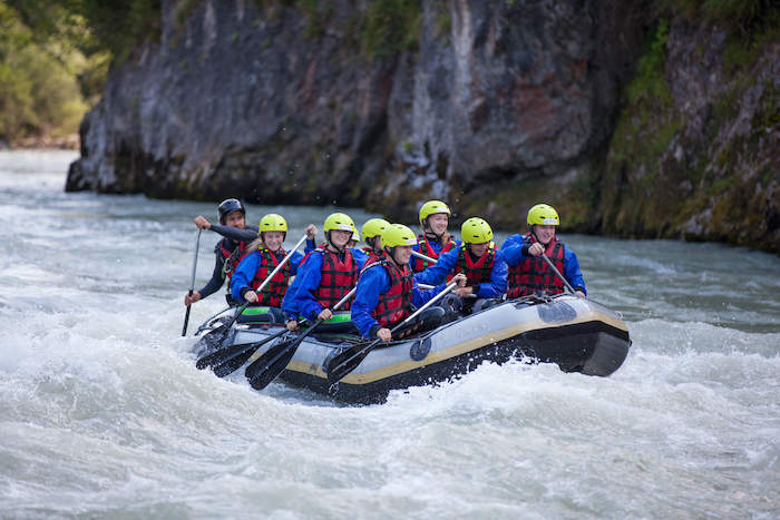 Participantes e instrutores no rio dentro do barco a fazer atividade de rafting