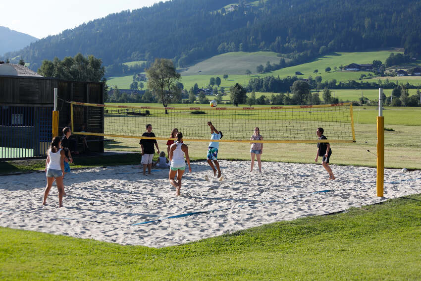 Jovens a jogar voleibol de praia em equipas na colónia de férias Julho