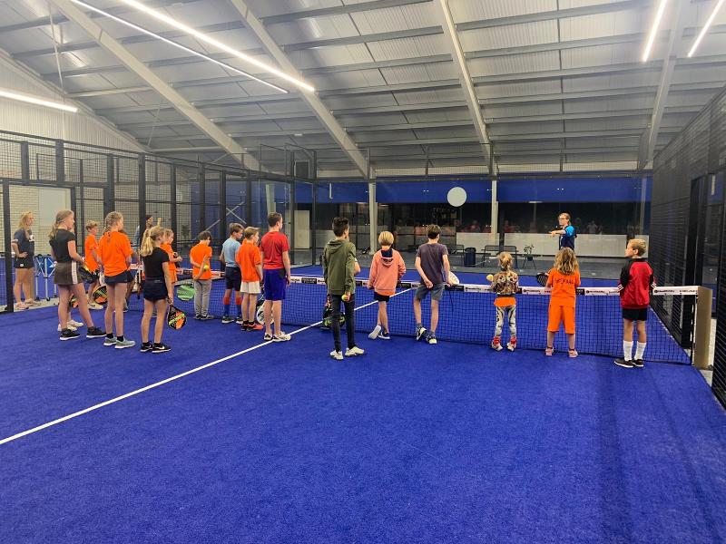 monitor a dar instruções de como jogar paddle no campo de férias ténis