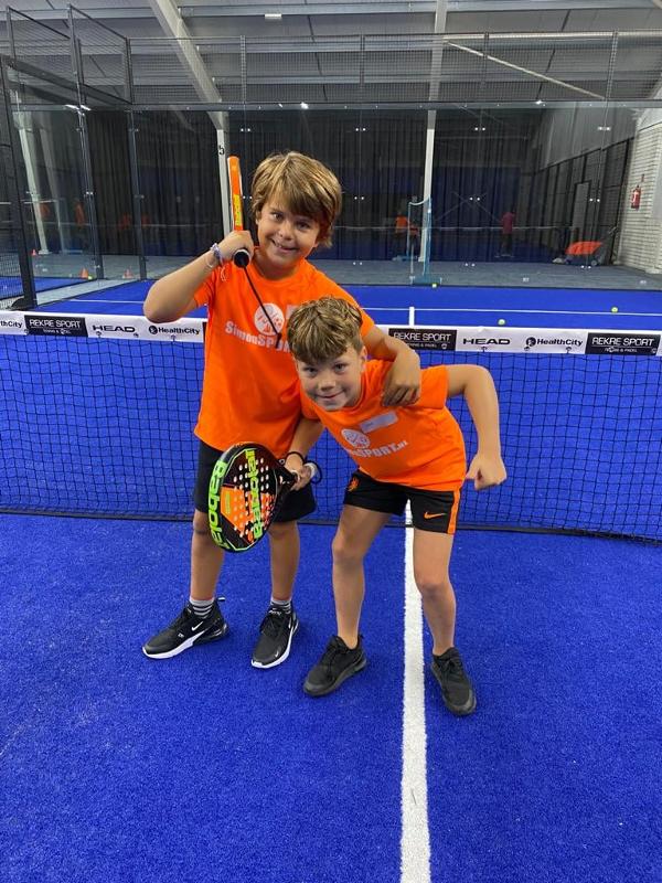 dois meninos pequenos a sorrirem para a foto antes do treino de paddle