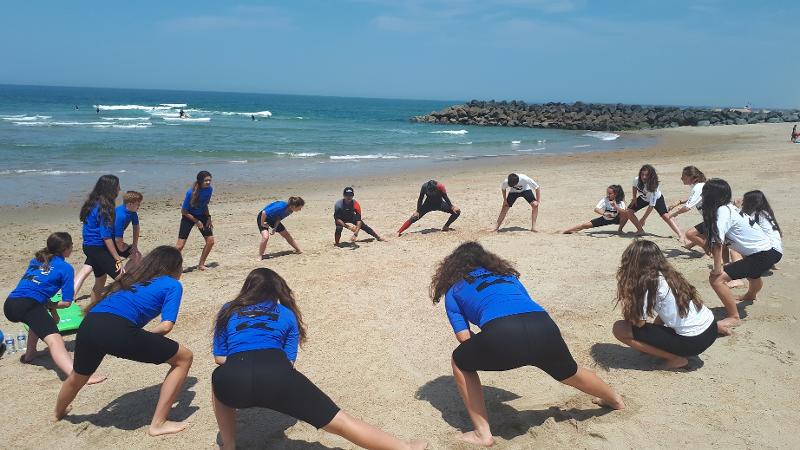 Participantes a aquecer na areia antes de começar a sessão de surf no surf camp Aljezur
