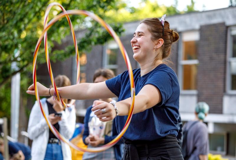 Jovem sorridente a divertir-se com hula hoop no campo de férias internacional