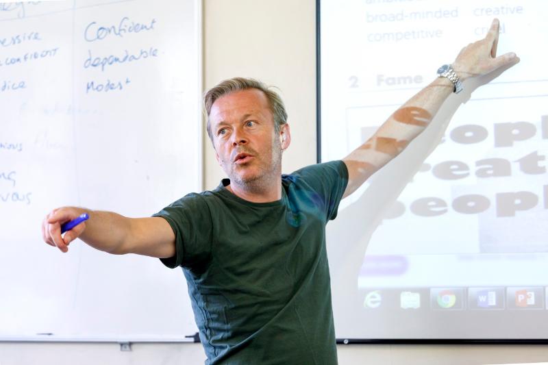 Professor a dar aula junto ao projetor no curso de línguas de Verão