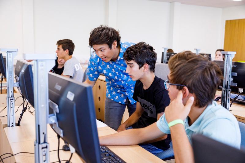 Jovens na sala de aula a fazer atividade interativa no computador no campo de férias em Inglaterra