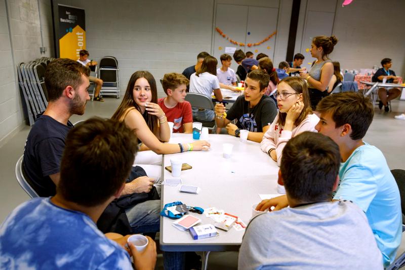 Crianças e monitor à volta da mesa a jogar às cartas no campo de férias internacional