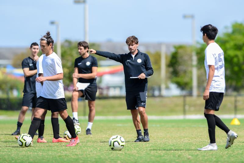 Treinador a dar indicações aos jogadores no treino do campo de férias