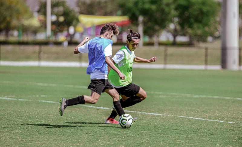 Defesa e avançado a disputar uma bola no campo de férias futebol 