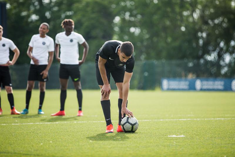 Jogador a preparar a bola para bater um penálti no treino de futebol do campo de férias internacional