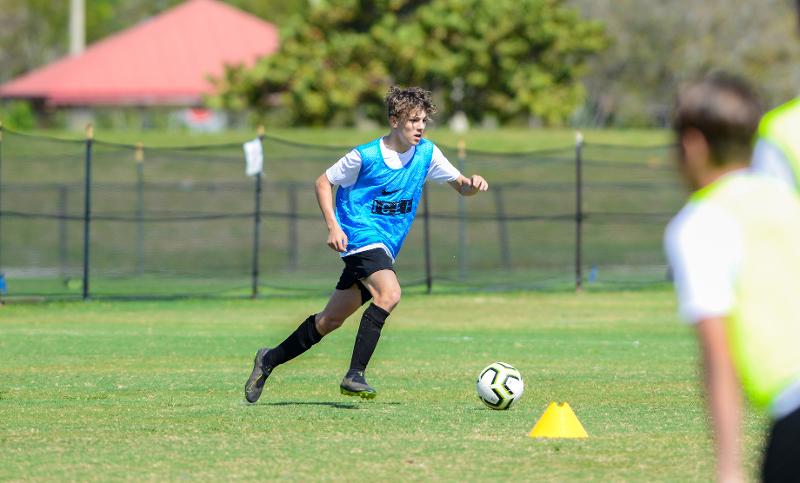Jogador a driblar a bola no treino do campo de férias futebol