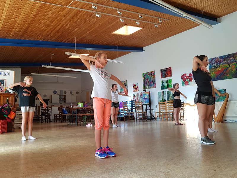 Participantes estão a fazer sessão de dança nas instalações do campo de férias