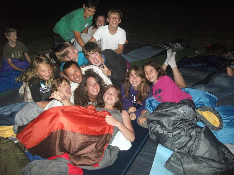 Grupo de jovens nos sacos de cama durante o acampamento noturno do campo de férias Santarém