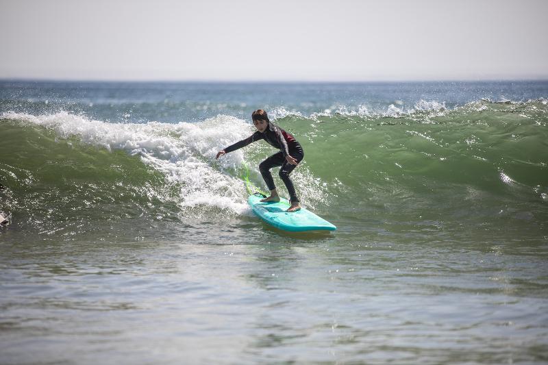menino em cima da prancha a apanhar onda no surf camp lisboa
