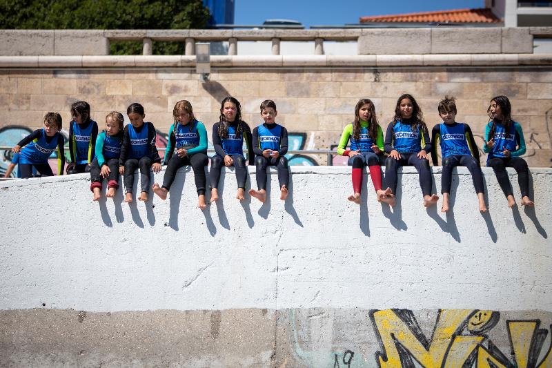 participantes mais novos sentados no muro depois de aula de surf no surf camp lisboa