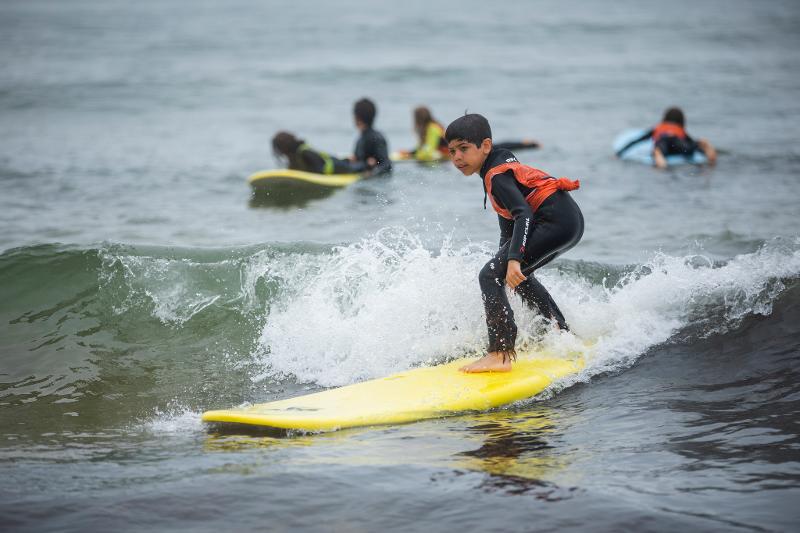 Criança na crista da onda durante o campo de férias de surf