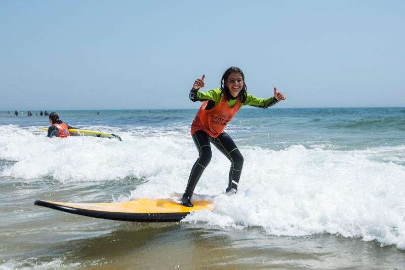 Menina a apanhar a primeira onda no campo de férias de surf