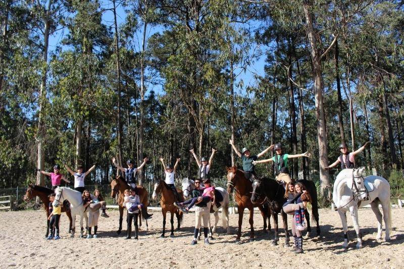 Participantes do campo de férias montados a cavalo a fazer dinâmica de grupo