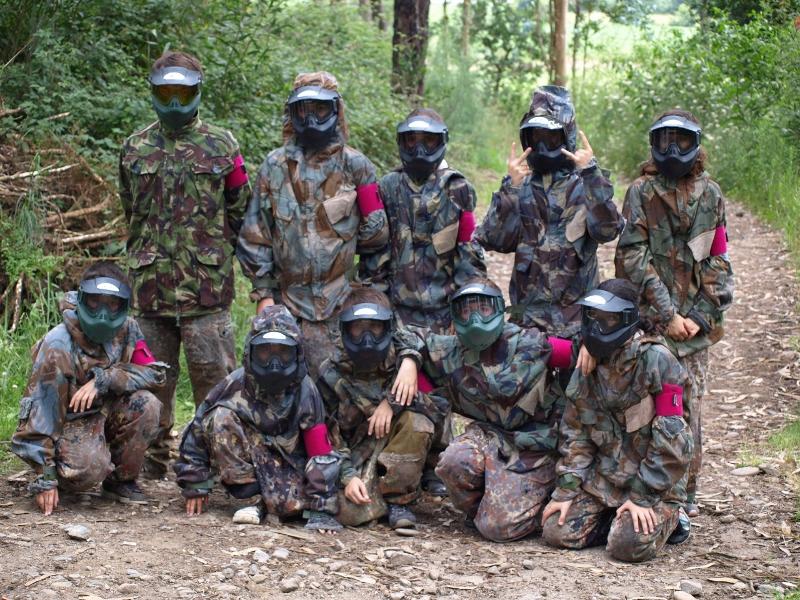 Crianças no campo de férias vestidas com fatos de tropa para um jogo de paintball