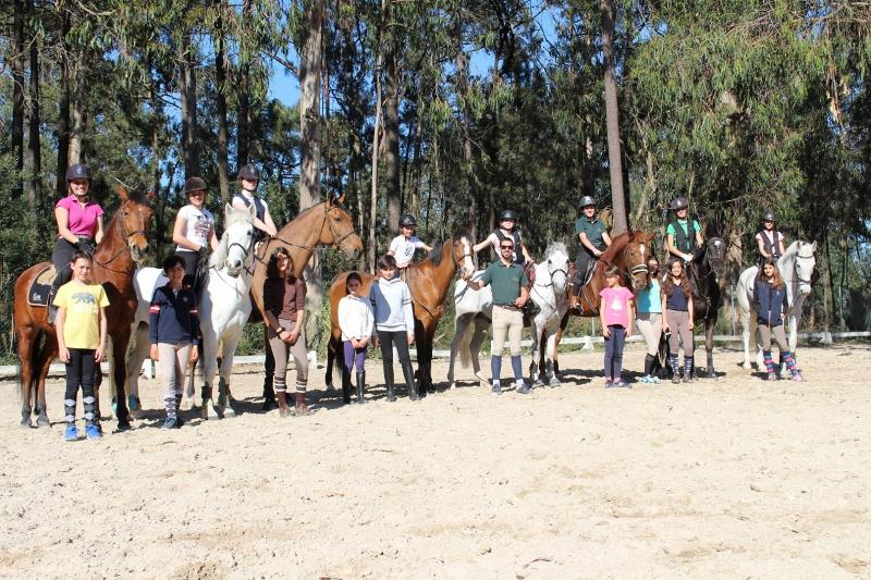Crianças no campo de férias de equitação junto aos cavalos no picadeiro