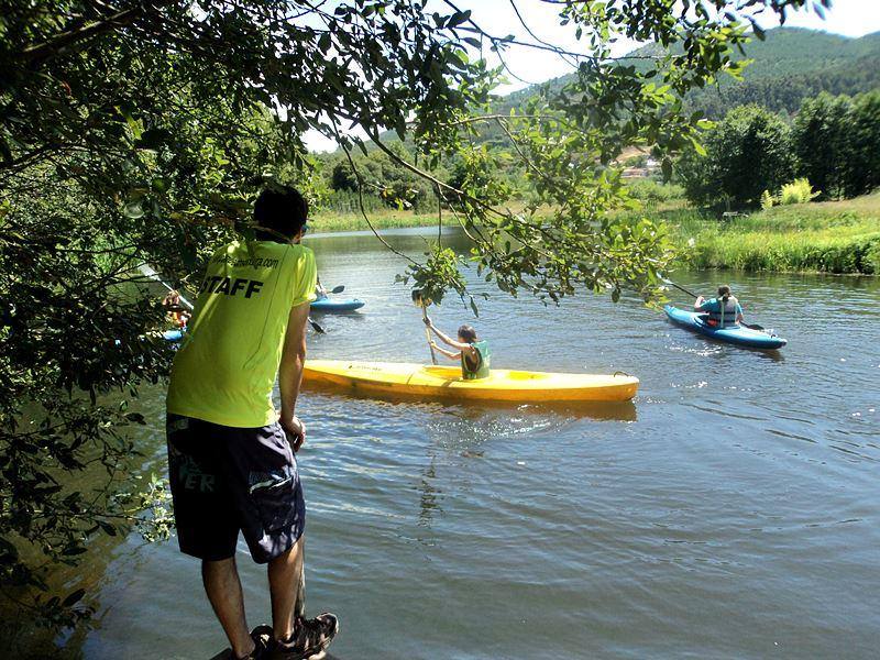 Monitor a supervisionar os participantes a fazer canoagem no rio