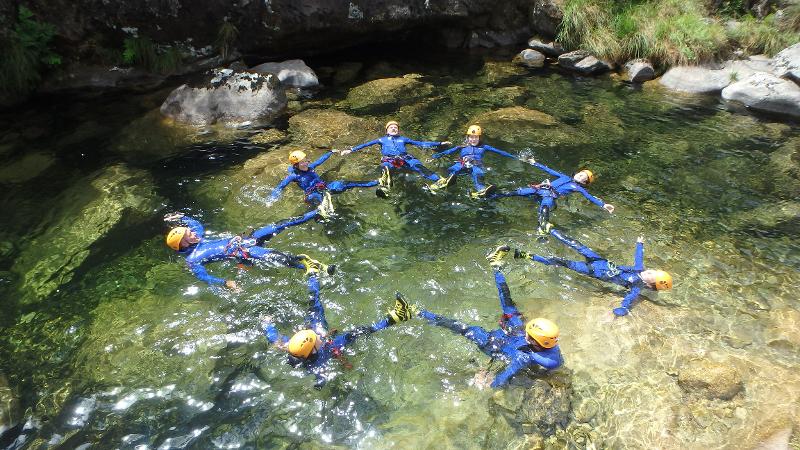 Participantes a fazer formação em estrela dentro do rio durante atividade de canyonning do campo de férias
