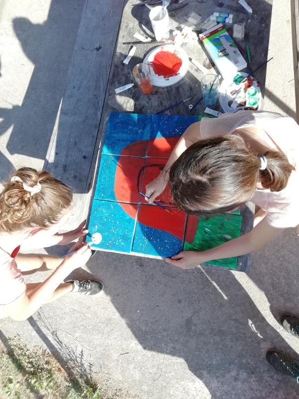 meninas a pintarem azulejos durante a atividade criativa na colónia de férias para adolescentes