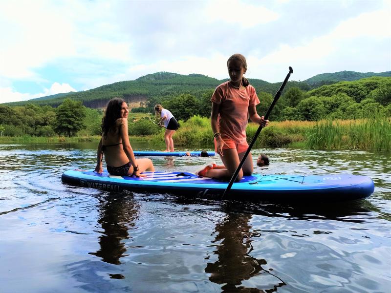 duas meninas em cima da prancha de SUP na colónia de férias para adolescentes