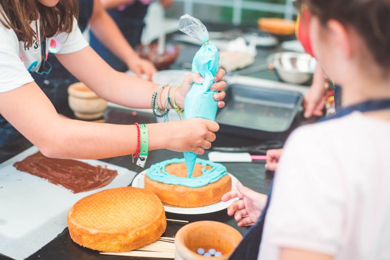 Criança apresenta a comida que preparou no campo de férias temático