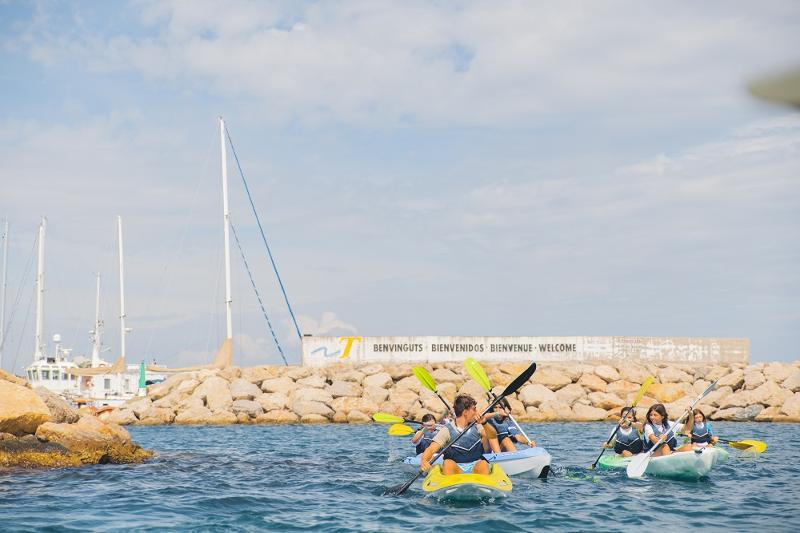 Crianças a remar no mar deitados na prancha de surf no campo de férias