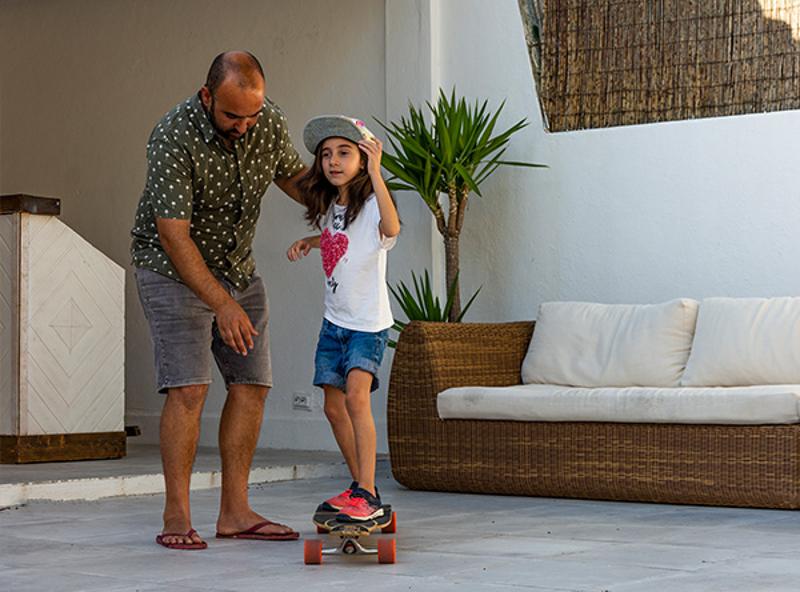 Criança a fazer sessão de skate no surfcamp com a ajuda do monitor