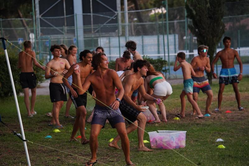  Na imagem, estão vários participantes a jogar balões de água uns aos outros durante o campo de férias com transporte acompanhado