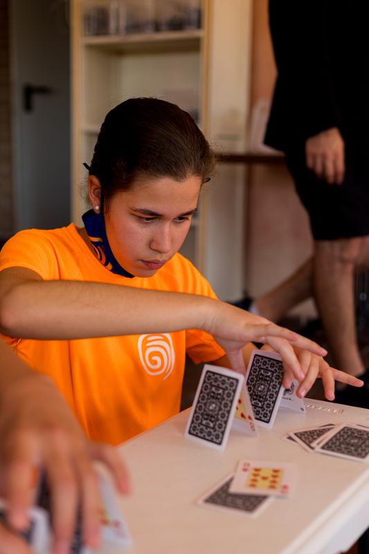 Criança a fazer jogo de equilíbrio com cartas no campo de férias criativo