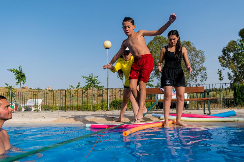 Crianças a fazer atividade de slackline na piscina do campo de férias