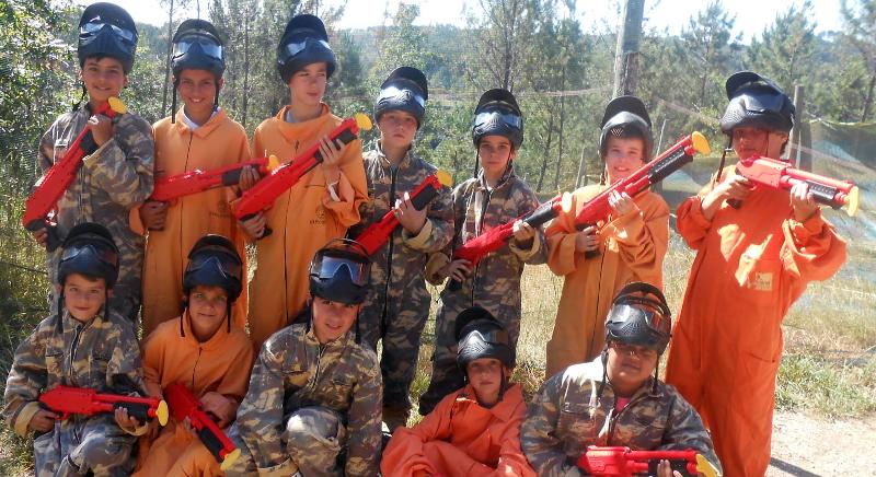 Participantes com equipamento de paintball preparados para a atividade no campo de férias