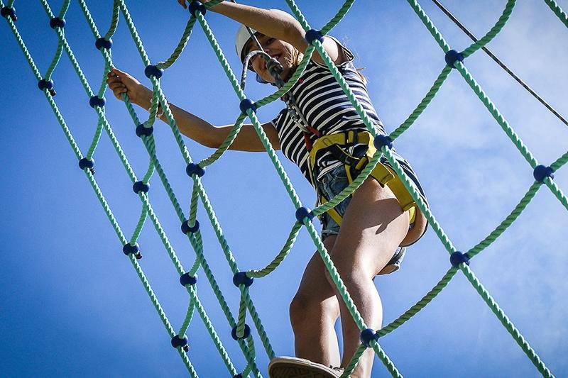 Menina a fazer atividade de aventura nas cordas durante o campo de férias