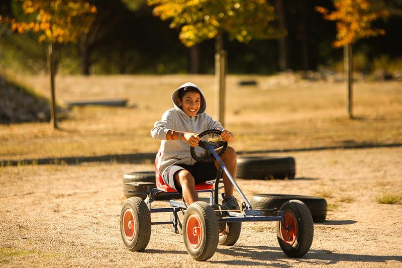 Menino sorridente a andar no kart durante o campo de férias