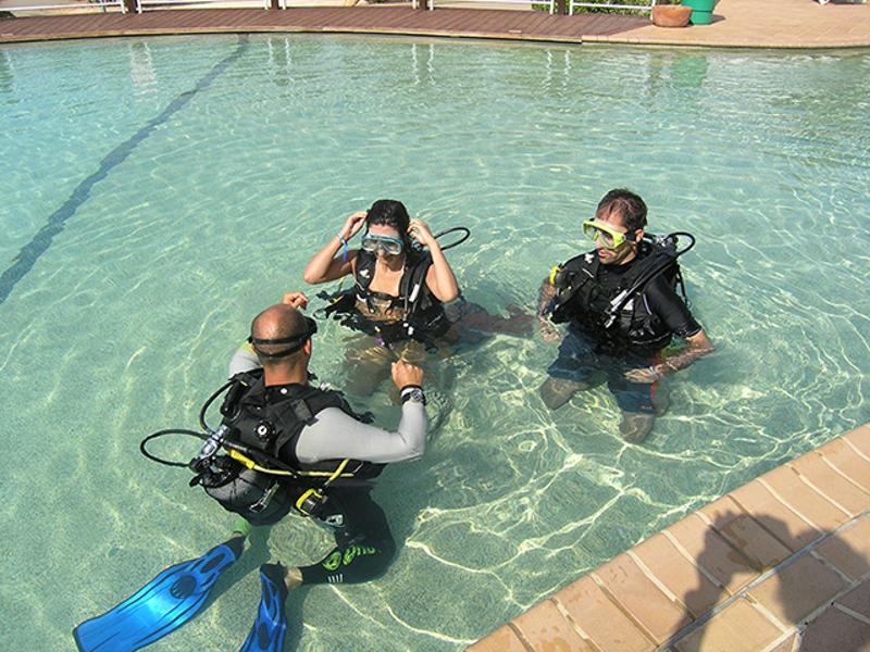 Instrutor e participantes na piscina no batismo de mergulho