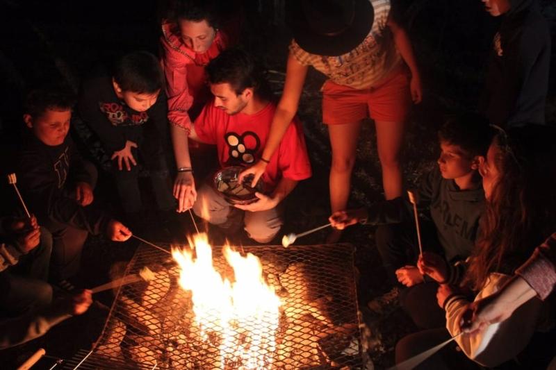 participante à volta da fogueira pela noite no campo de férias Coimbra