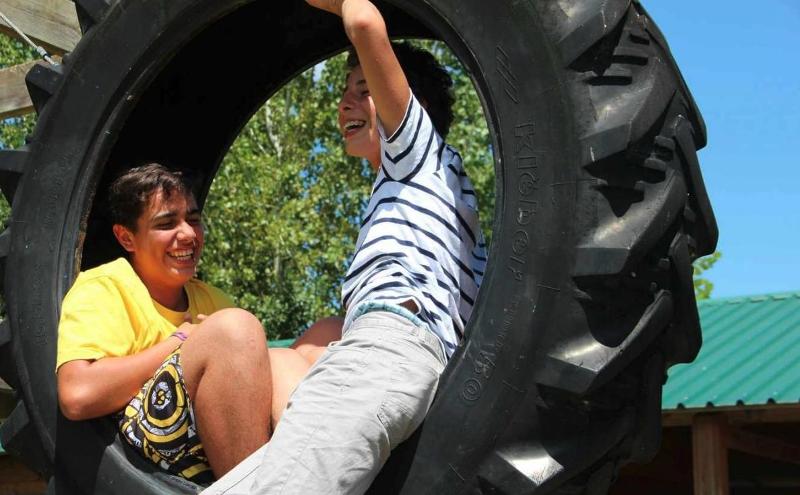 Jovens a fazer um jogo no pneu durante o campo de férias de aventura